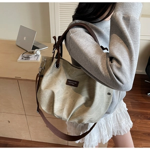 Close-up of canvas tote bag with brown leather straps and branded label in office setting