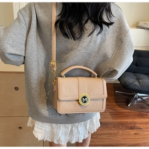 Detail of beige quilted faux leather crossbody bag with gold-tone M logo hardware decoration