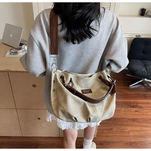 Detail view of large beige canvas tote with pleats, brown leather handle, and wide strap