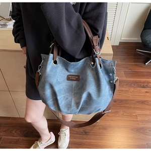 Detail of vintage blue tote bag showing washed denim texture and brown leather brand tag