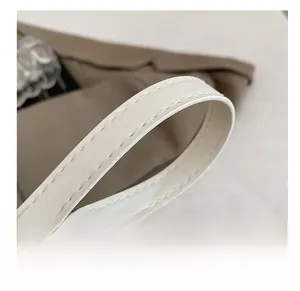 Gros plan sur la bandoulière en cuir blanc avec texture fine et coutures de précision
