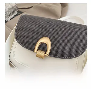 Détail du sac selle en patchwork avec rabat en tissu gris et boucle dorée en forme de U