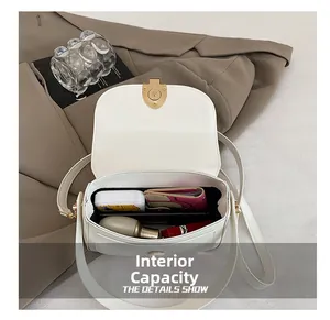 Capacité interne du sac selle blanc montrant les objets essentiels et le fermoir doré