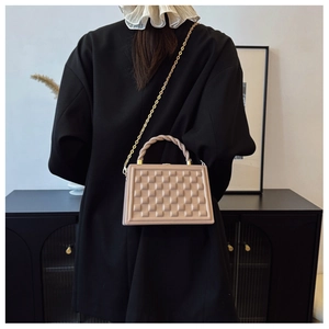 Detail showing beige 3D geometric quilted box bag with gold chain and woven handle