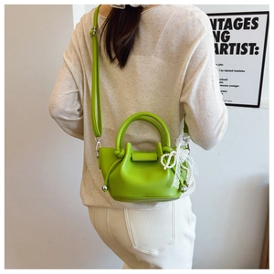 Détail du sac seau vert en cuir avec nœud en dentelle perlé et bandoulière réglable