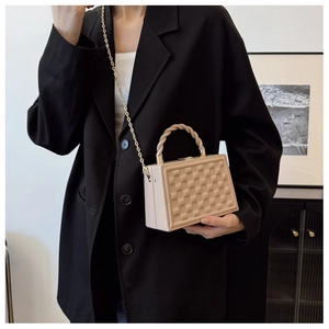 Detail view of beige box bag with 3D geometric texture and golden chain strap
