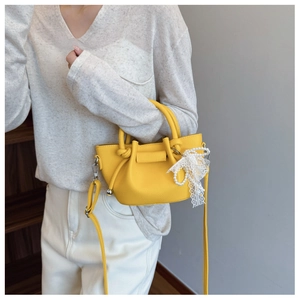Détail du sac seau jaune en cuir avec nœud en dentelle perle et bandoulière réglable