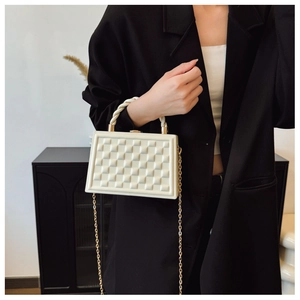 Close-up of beige quilted box bag with golden chain strap and woven handle detail