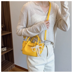 Gros plan du sac jaune vif à motif litchi avec breloques en perles et dentelle en décor
