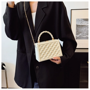 Close-up of a white quilted hard-shell box bag with gold chain and spiral handle