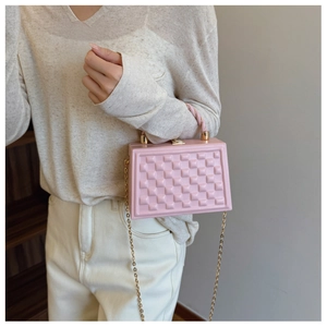 Pink quilted box bag with a woven handle and gold chain strap shown on a model
