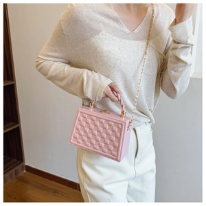 Detail of pink quilted box bag with golden metal lock and woven handle strap