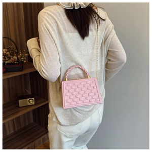 Pink quilted crossbody bag with 3D cube texture and twisted handle shown on model