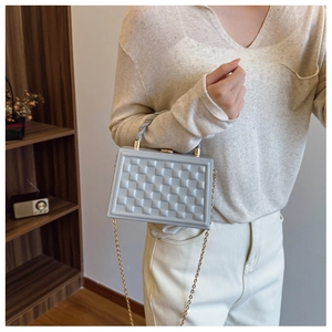 Detail of light blue box bag with 3D geometric grid texture and golden chain strap
