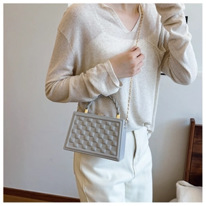 Detail of grey crossbody bag with 3D geometric embossed pattern and woven handle