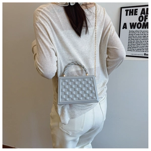Fashionable grey quilted crossbody box bag styled with a gold chain strap and top handle