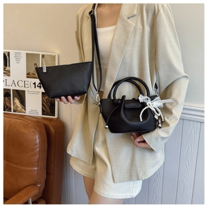 Détail du sac seau noir en cuir litchi avec pendentif perle et petit porte-monnaie assorti