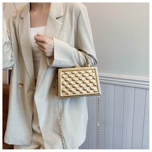 Detail of matte gold box bag with pyramid studs and twisted metal top handle