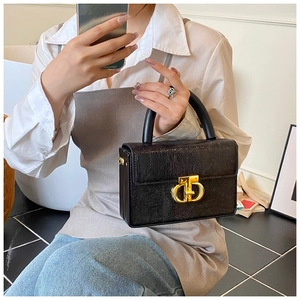 Dettaglio della trama a lucertola e chiusura dorata su borsa a mano nera elegante