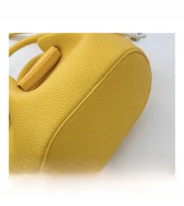 Détail du sac en cuir litchi jaune montrant les coutures précises et l'ornement en perle