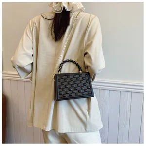 Detail of black quilted box handbag with gold chain strap and textured diamond pattern