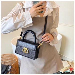Dettaglio della mini borsa a scatola nera goffrata con chiusura circolare a G dorata