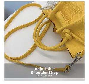 Détail du sac seau jaune en cuir avec bandoulière réglable et ornement de perle