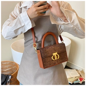 Borsa a mano marrone in pelle testurizzata con fibbia dorata e manico tondo indossata
