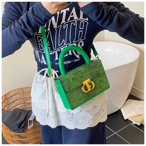 Dettaglio della borsa verde intrecciata con fibbia metallica a forma di T dorata