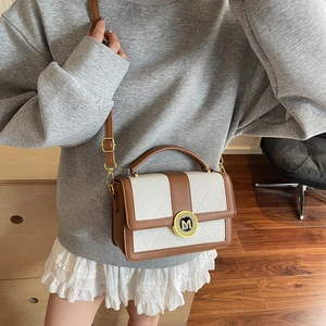 Chic two-tone quilted leather crossbody bag with a gold M-shaped metal buckle detail