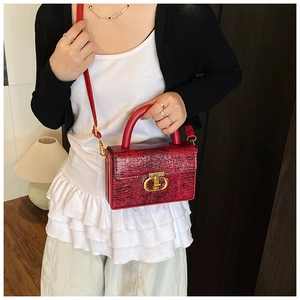 Dettaglio di una borsa a tracolla rossa in pelle testurizzata con fibbia dorata su modella