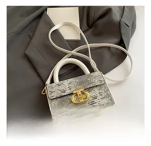 Dettaglio della borsa a scatola bianca con patta grigio metallizzato e chiusura CD dorata