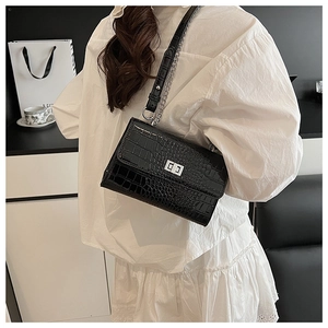 Detail of black croc-effect texture with silver rectangular lock on crossbody bag