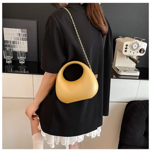 Detail of crescent acrylic evening bag in mustard yellow with golden chain strap