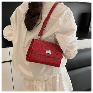 Lifestyle shot of a red crocodile pattern crossbody bag with silver chain and metal clasp