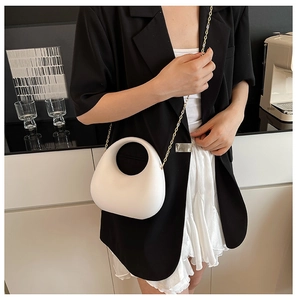 Detailed view of a white crescent acrylic handbag with round handle and gold chain strap
