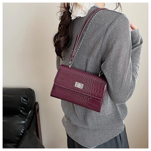 Detail of burgundy crocodile pattern bag with silver twist lock and chain strap