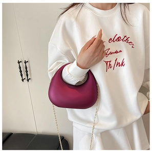 Detail view of fuchsia acrylic crescent evening bag with round handle and gold chain strap