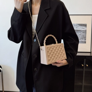 Beige quilted box bag with a woven handle and gold chain strap carried by a model