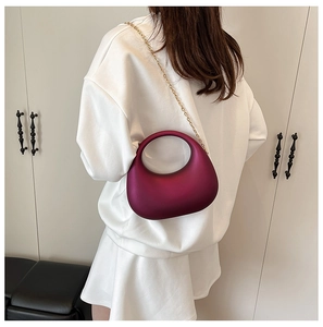 Detail of fuchsia acrylic crescent evening bag with gold chain and round handle on model