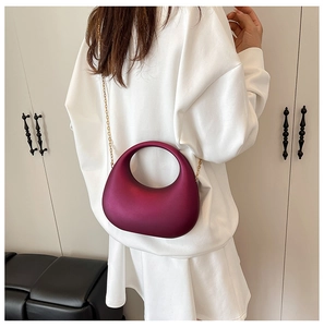 Chic dark burgundy crescent acrylic evening bag with gold chain strap shown on model