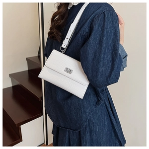 Detailed view of white crocodile pattern shoulder bag with silver turn-lock on a model
