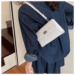 Detail of white crocodile pattern shoulder bag with silver metal turn-lock and chain strap