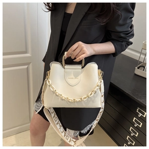 Detail of cream leather handbag with gold metal D-handle and resin chain decoration