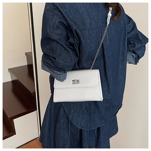 Detailed close-up of white crocodile pattern shoulder bag with silver metal twist lock