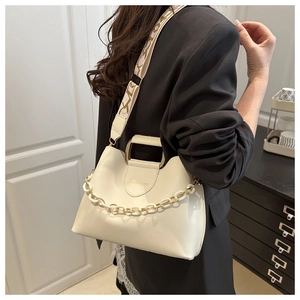Close-up of beige bucket bag with chunky plastic chain and patterned wide shoulder strap