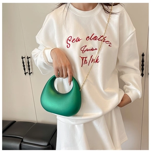 Detail of vibrant green acrylic half-moon evening bag with fine gold chain strap