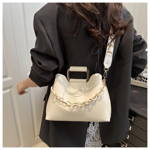 Close-up of cream bucket bag with wavy rim, gold chain, and lettered wide strap