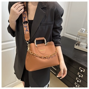 Detail of brown leather bucket bag featuring gold chain and floral wide shoulder strap