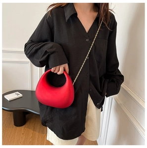 Chic red half-moon hobo bag with gold chain strap carried by a model in a stylish setting